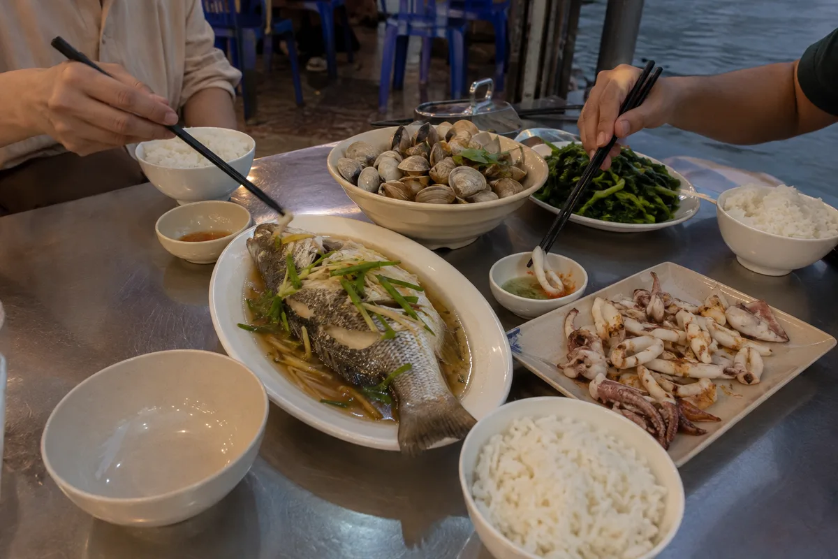 A shared coastal meal with steamed shellfish fish vegetables and rice